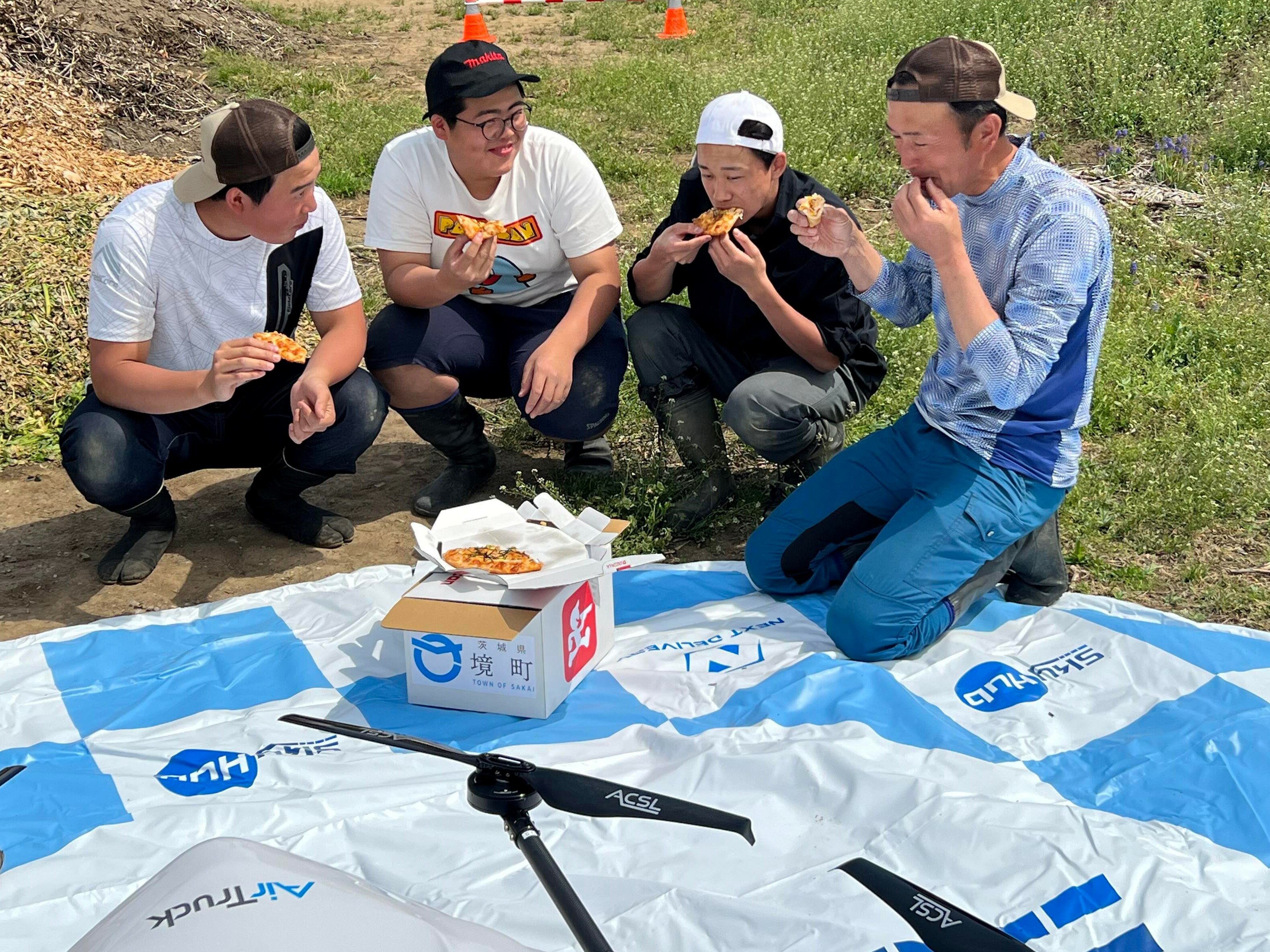 ドローン配送されたピザを食べる住民.jpg